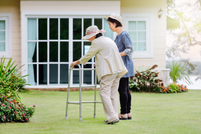senior woman exercise walking in backyard with her caregiver